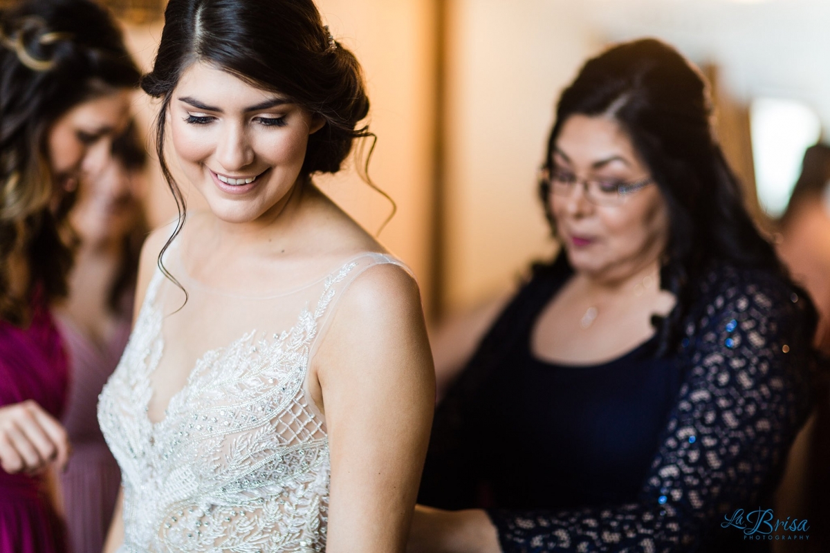 mother of bride helping bride get dressed