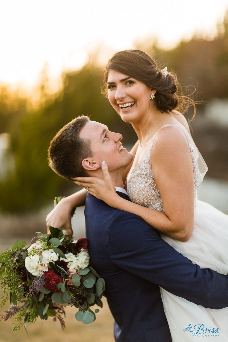 Groom lifting bride with bouquet stone crest wedding