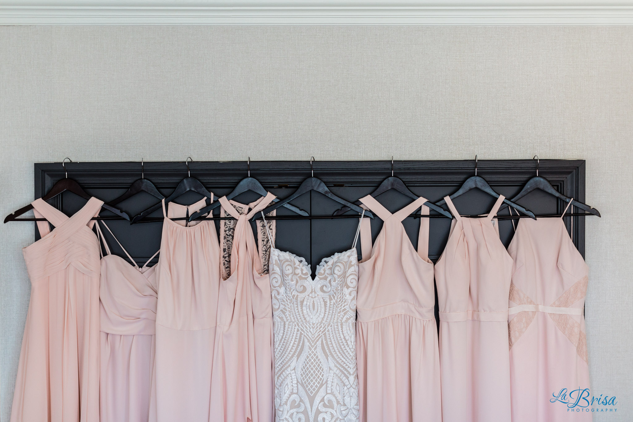 wedding gown hung next to peach bridesmaids dresses